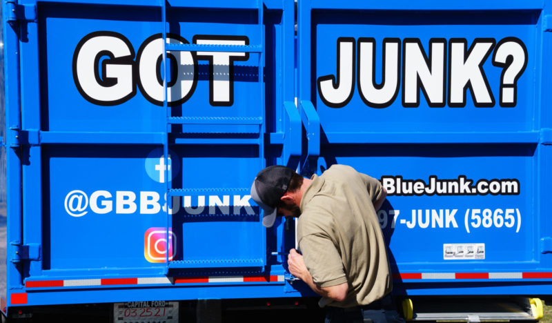 Dump truck is being closed by Go Big Blue Junk Removal worker after a clean out