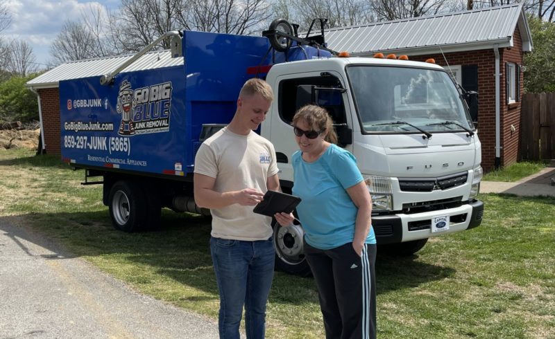 Employee with customer before a junk removal job going over price with an estimate