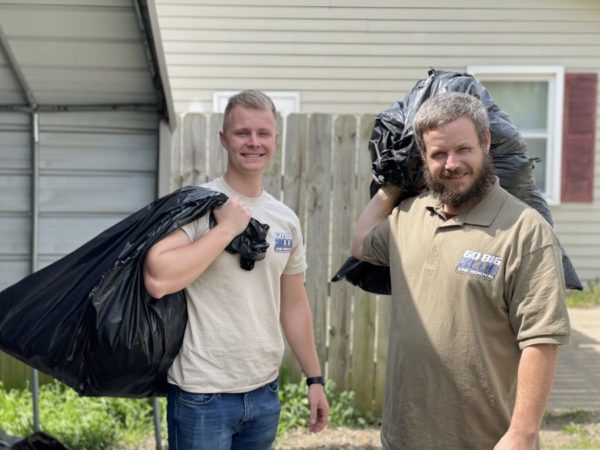 Go Big Blue junk removal team holding trash bags ready to haul away